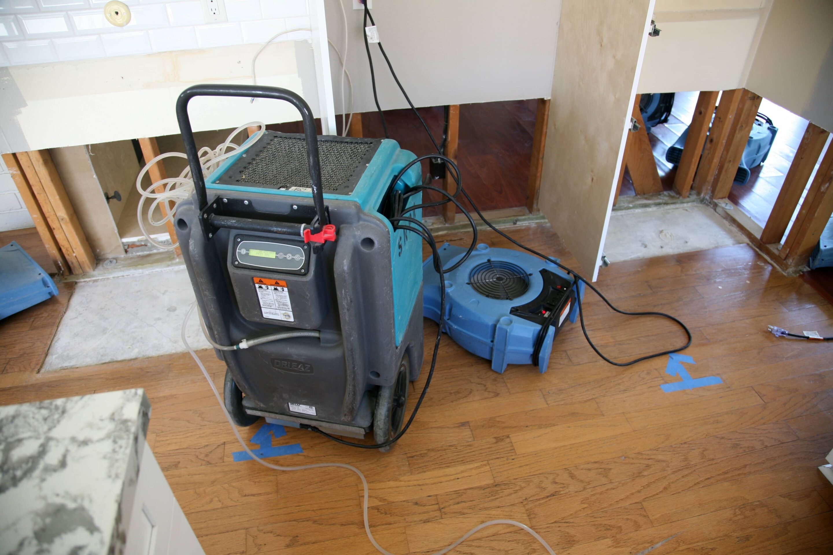 Industrial air movers and dehumidifiers drying a water damaged room after flood cleanup